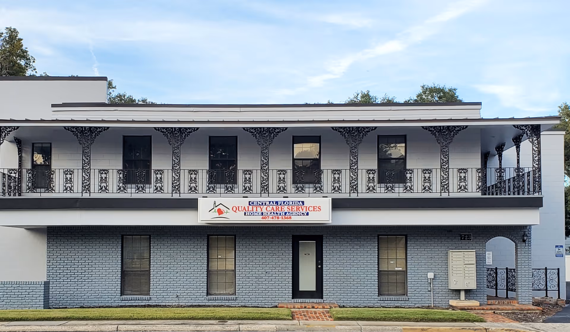 Two-story building with decorative balcony railings and a care services sign.