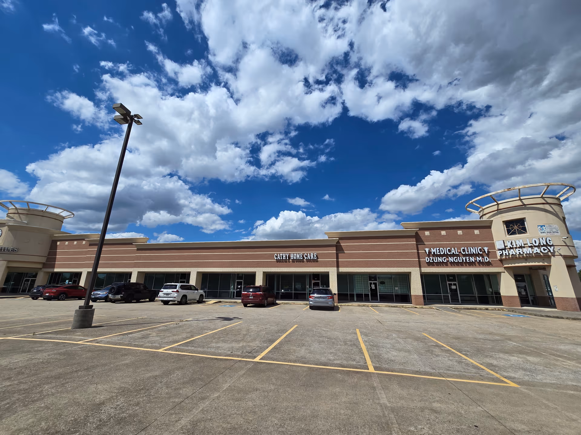 Exterior view of a strip plaza with Cathy Home Care sign, medical clinic, pharmacy, and parking.