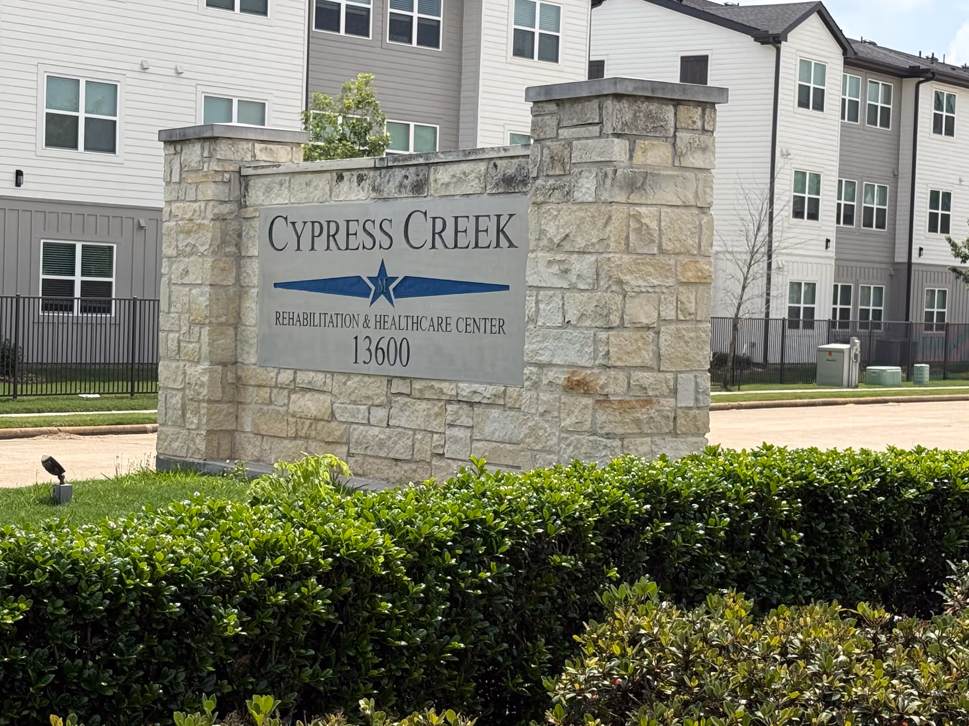 Stone sign reading Cypress Creek Rehabilitation & Healthcare Center in front of a multi-story building.