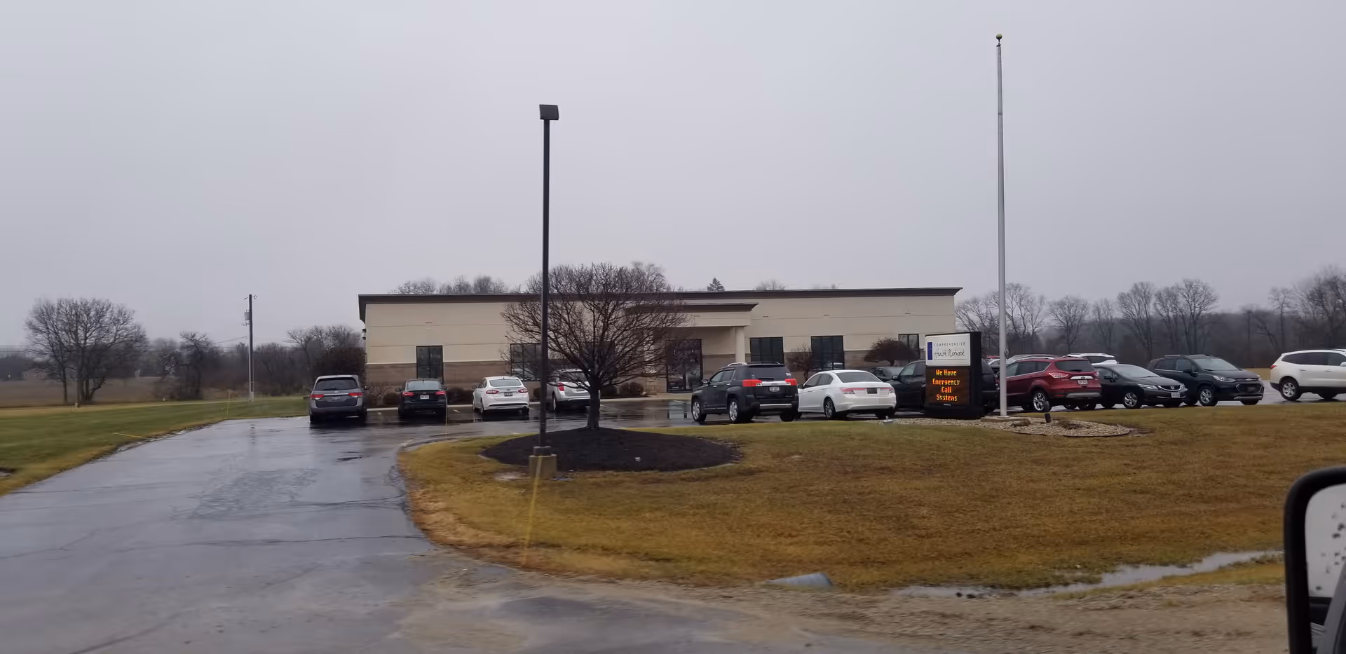 Exterior view of a Comprehensive Health Network facility with cars parked in front.