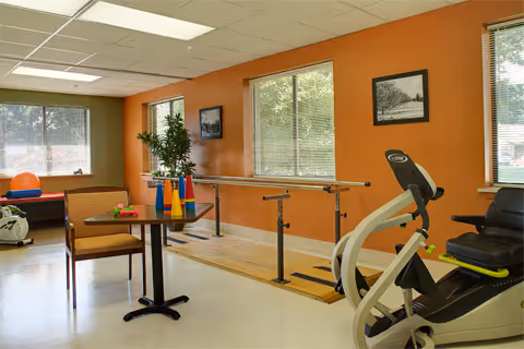 Interior therapy room at Medilodge of Portage with parallel bars and exercise bike.