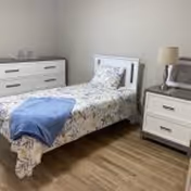 A single bed with floral bedspread, two nightstands, and a dresser in a small bedroom.