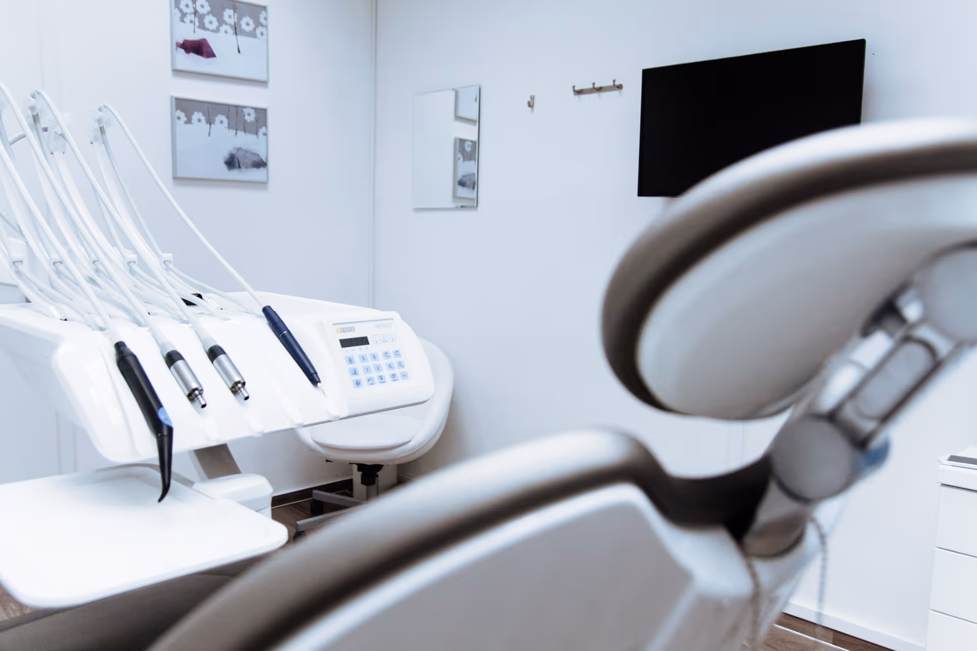 Dental chair and equipment in a clean treatment room with wall decor.