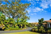 Sunny exterior view of The Meadows at Cypress Gardens with lush landscaping and red tile roofs.