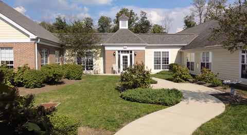 Exterior view of Abbington of Pickerington with curved walkway, landscaping, and front entrance.