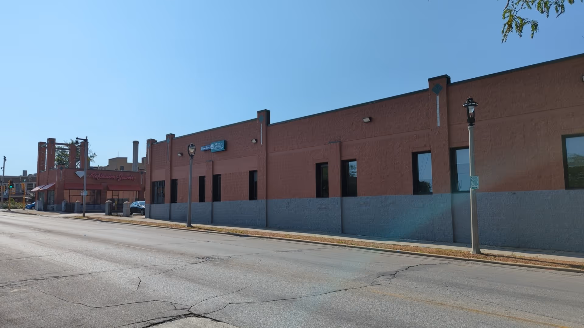 Exterior view of a red-brick health center along a quiet street.