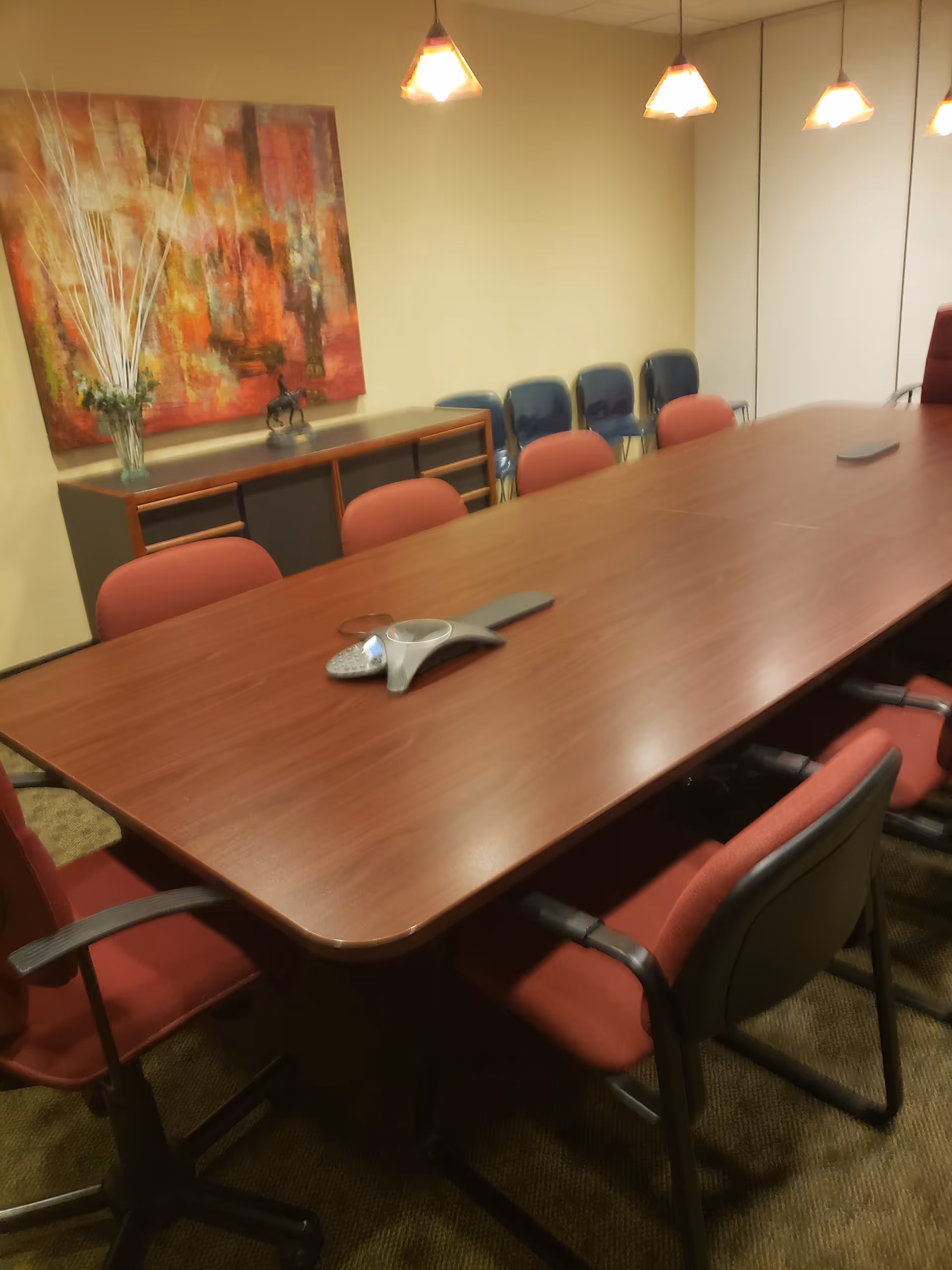 Long conference-style table with red chairs in a senior facility dining room.