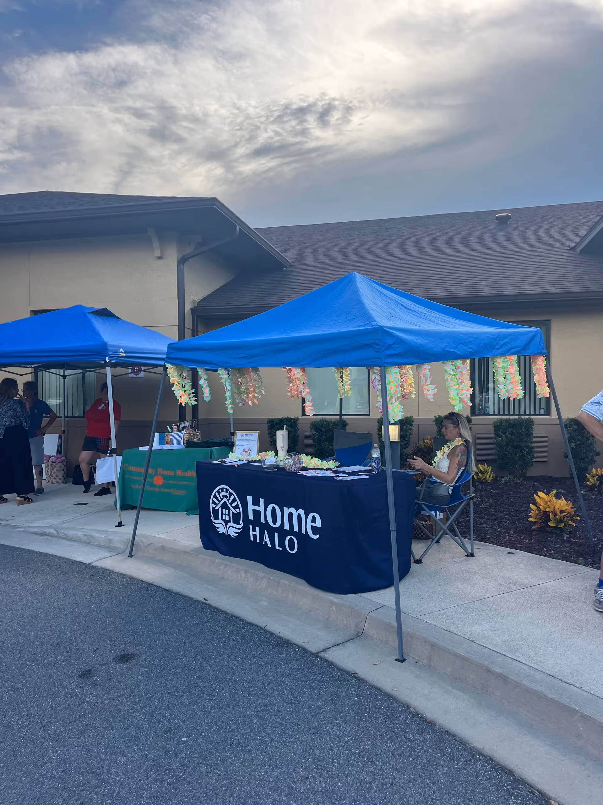 Blue canopied outdoor booths with a Home Halo table outside a senior living facility.