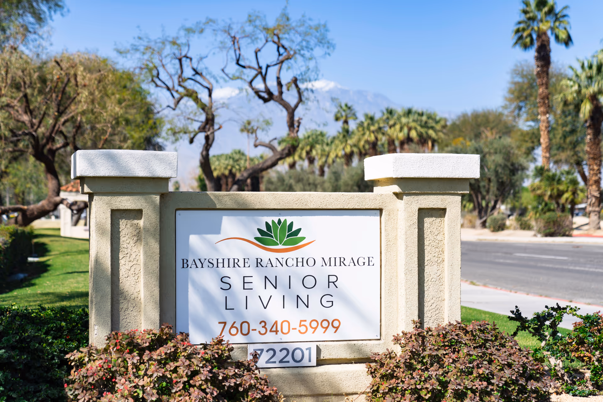 Stone entrance sign reads Bayshire Rancho Mirage Senior Living with landscaping and trees.