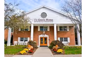 Front view of The Green Home senior living facility with brick entrance and landscaped walkway.
