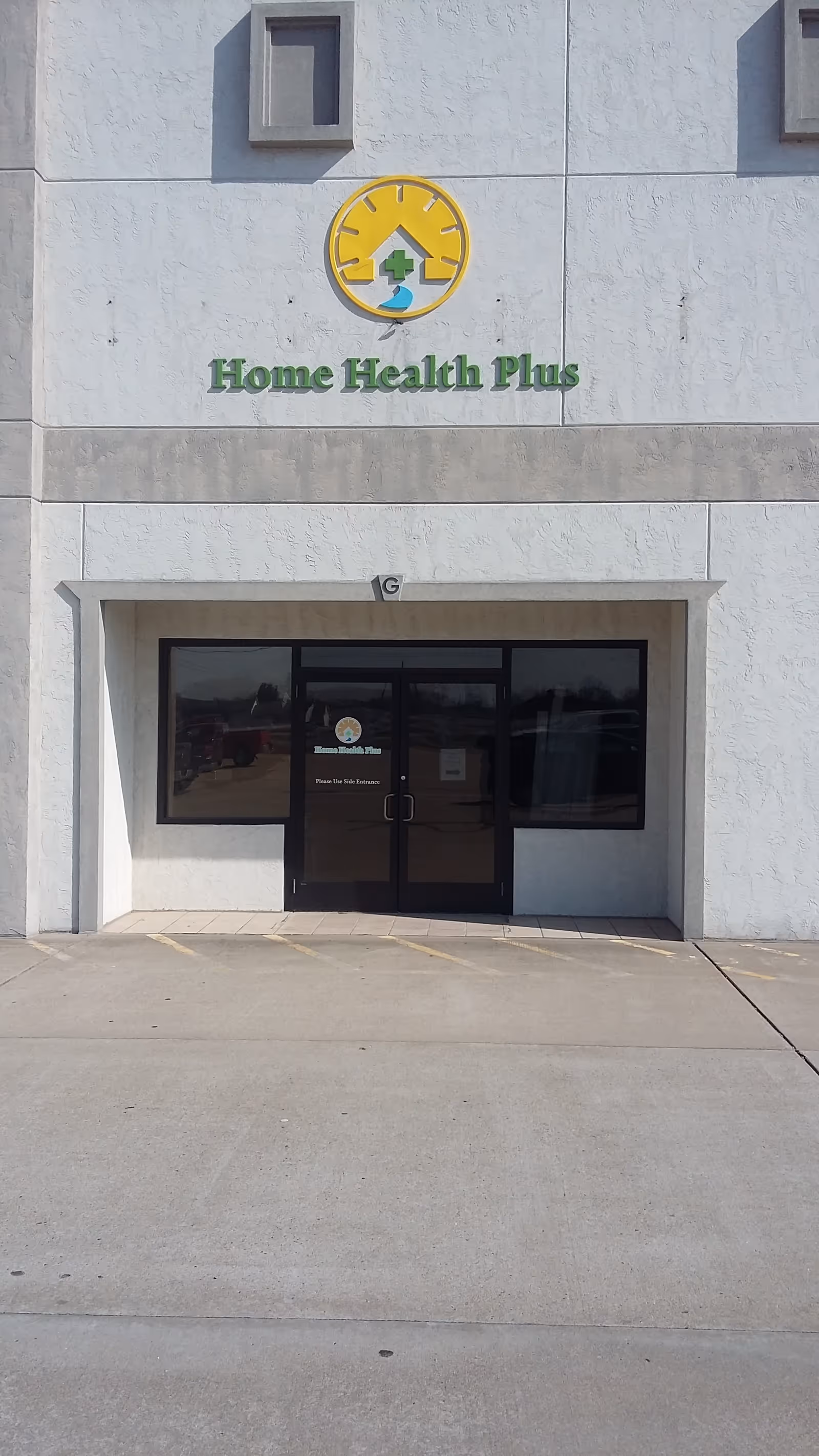 Exterior view of a building entrance with a Home Health Plus sign.