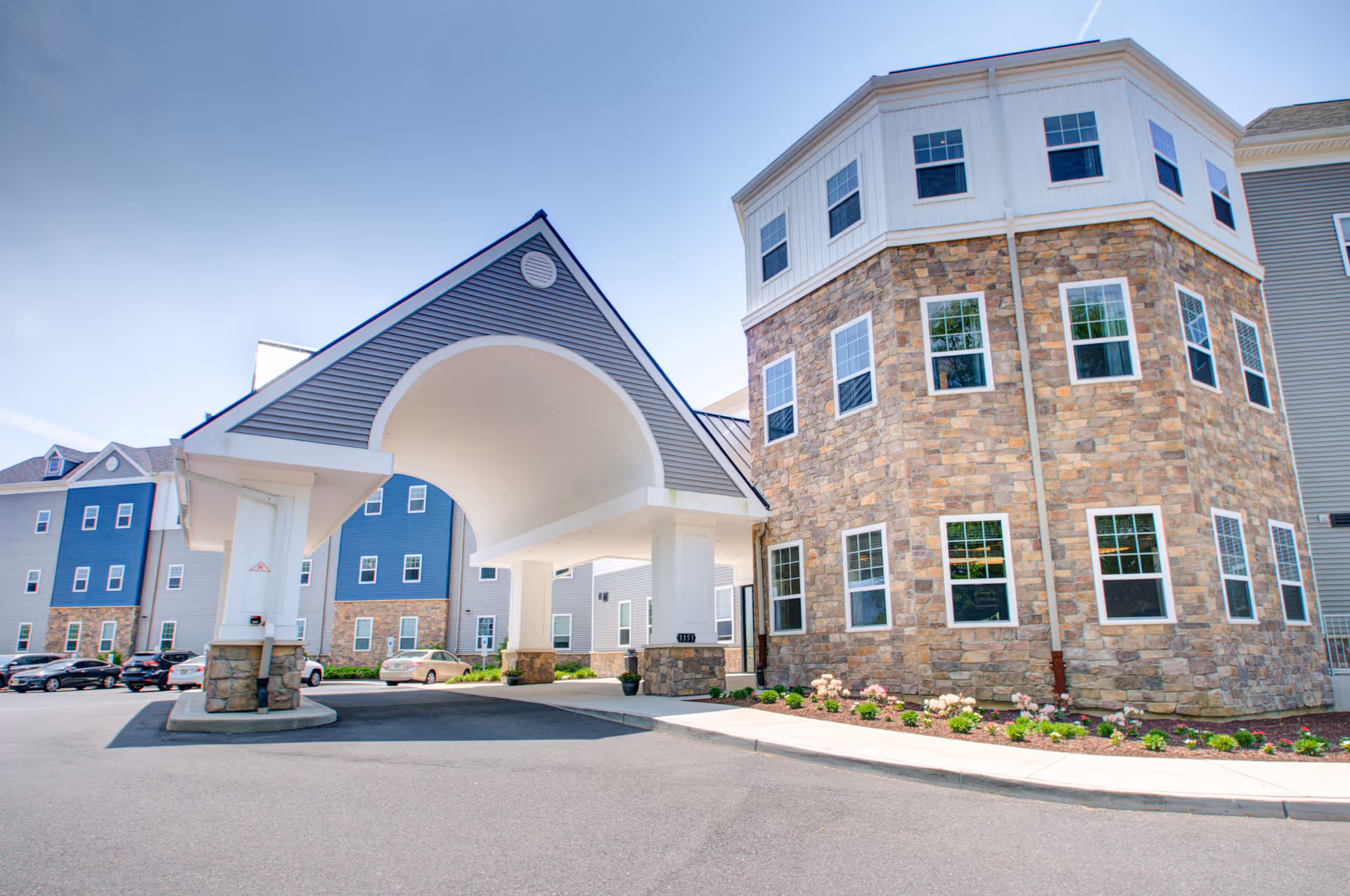 Exterior view of a senior living facility with a covered porte-cochere entrance.