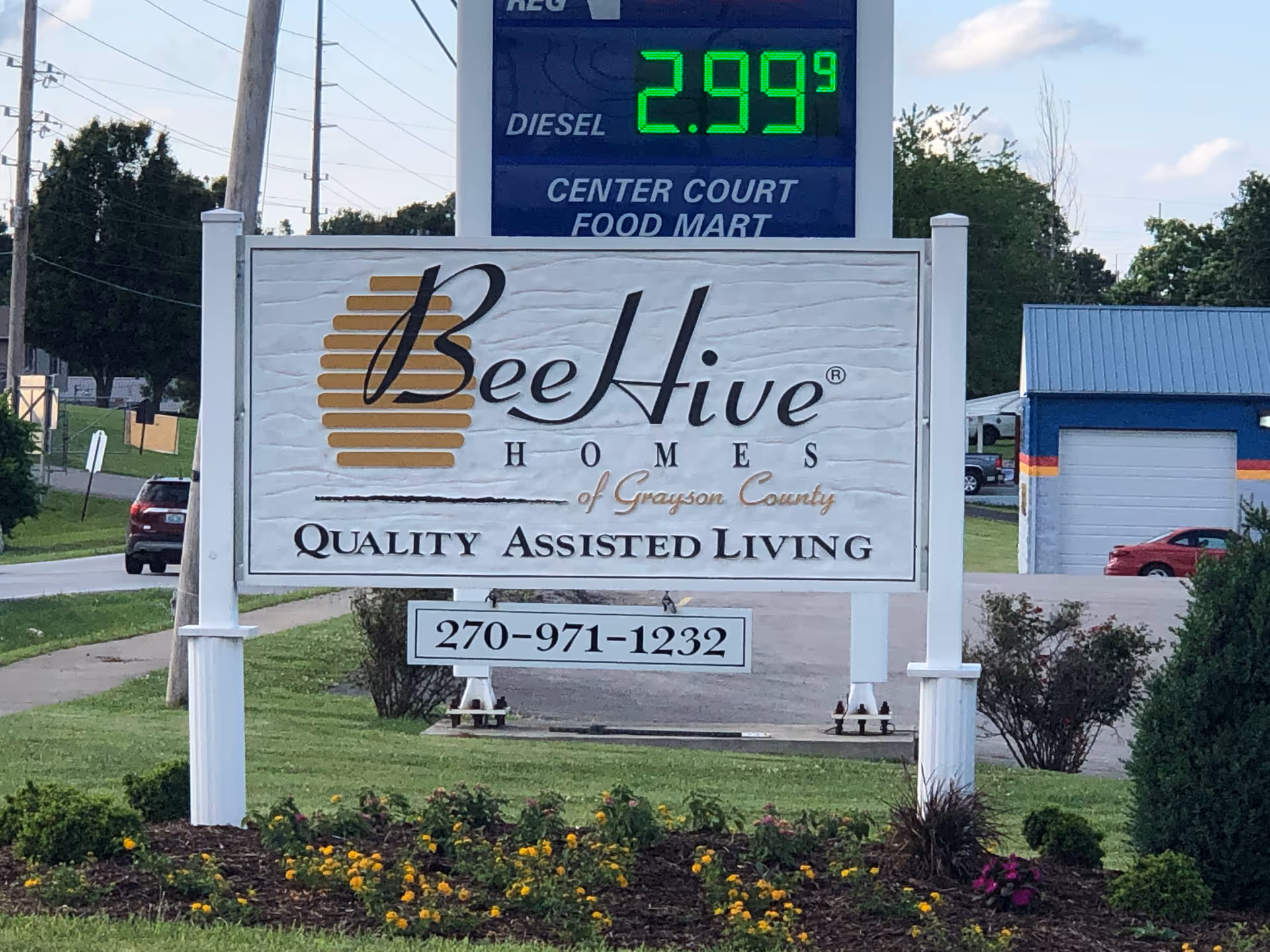 BeeHive Homes sign with logo and phone number in a landscaped front yard.
