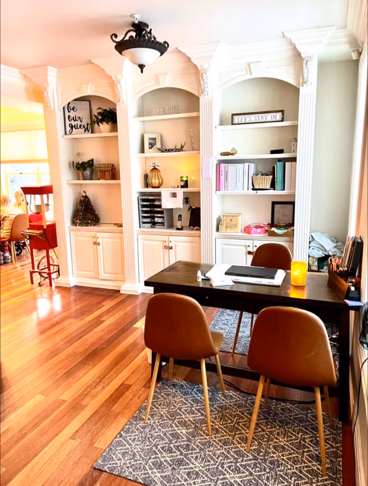 Bright interior with built-in shelves, a dark desk, and three brown chairs in a common area.