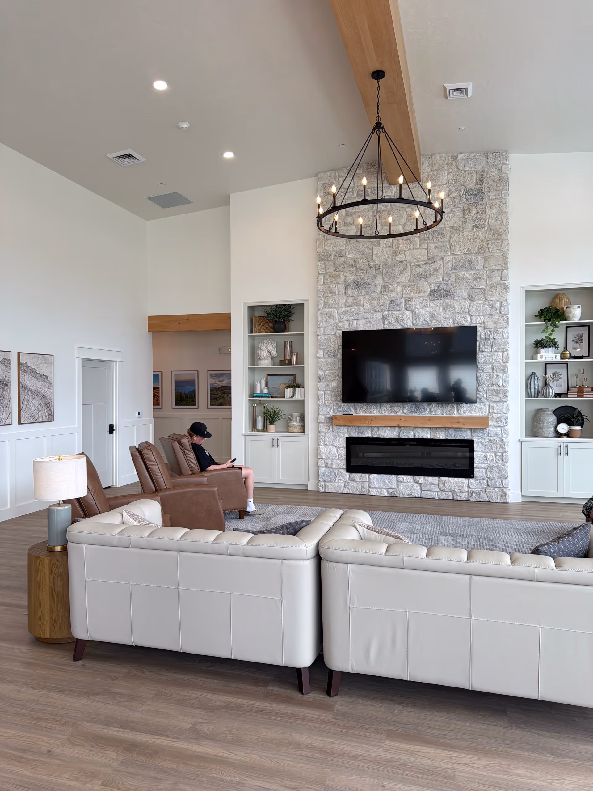 Bright, airy living room with a stone fireplace, mounted TV, and comfortable seating.