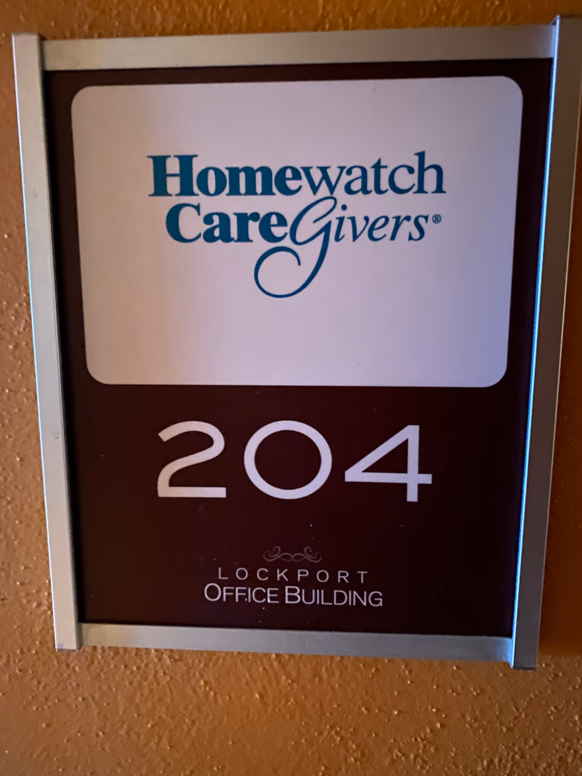 Wall-mounted sign displaying Homewatch CareGivers and room 204.