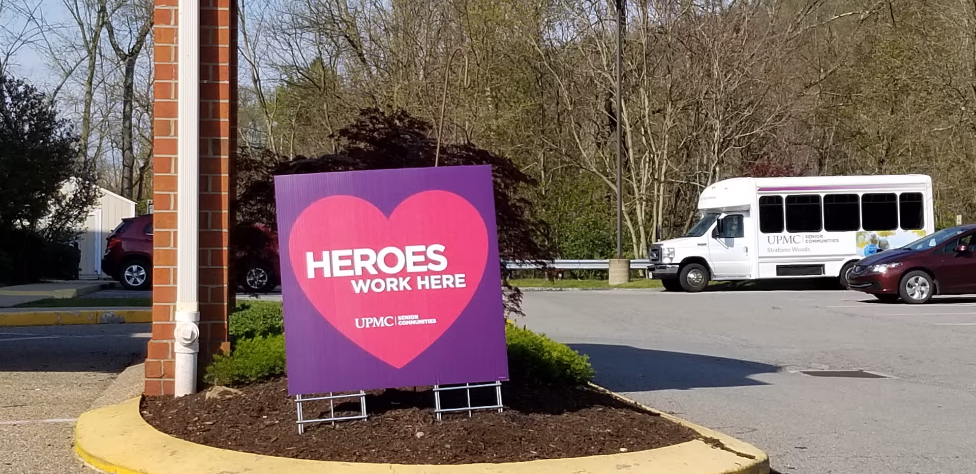 Purple heart-shaped sign reads HEROES WORK HERE outside Strabane Woods of Washington