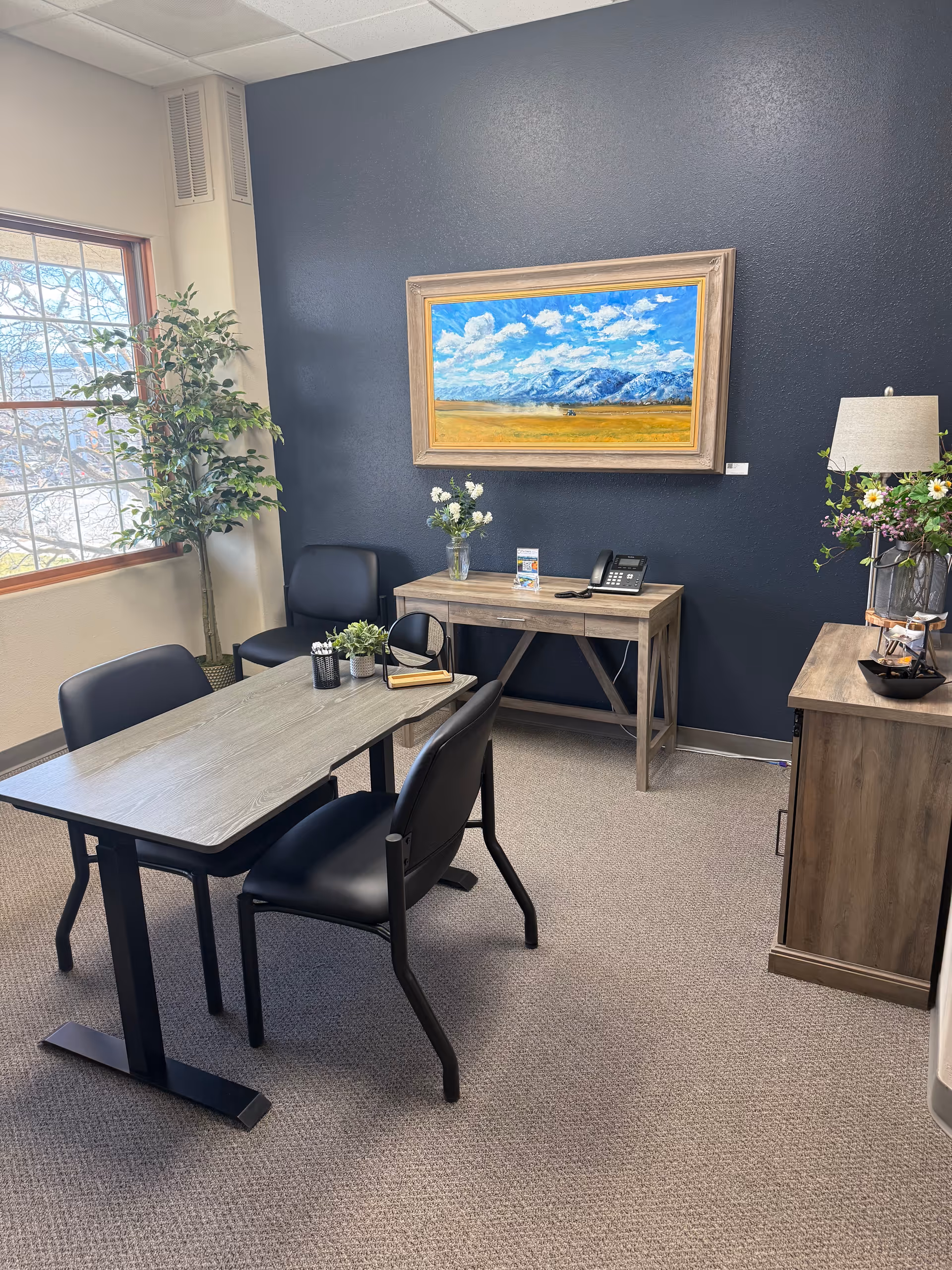 A small meeting area with a rectangular table, black chairs, and a dark blue accent wall.