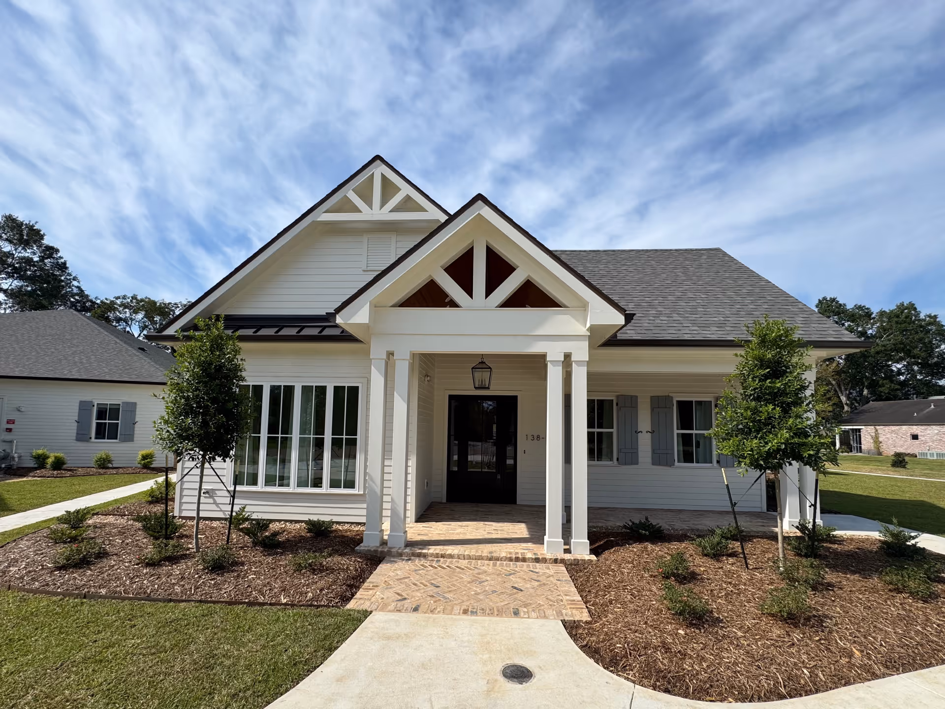 Front view of a white assisted living facility with a covered entrance and landscaped yard