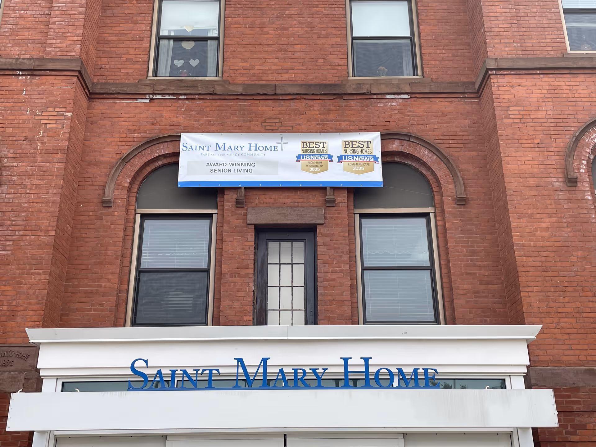 Brick exterior of a senior living facility with a banner above entrance.