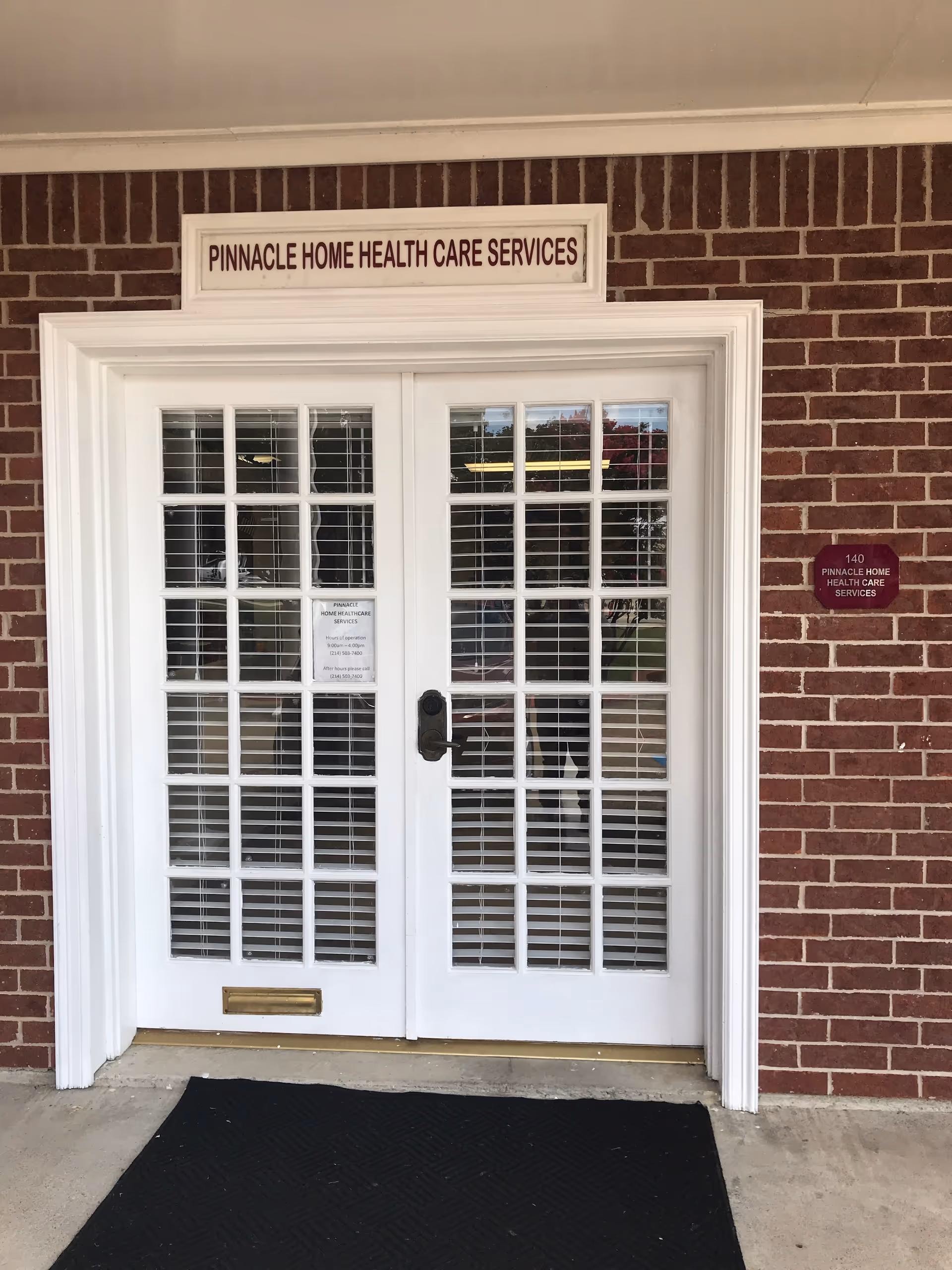 White double doors with glass panes, brick exterior, and a Pinnacle Home Health Care Services sign.