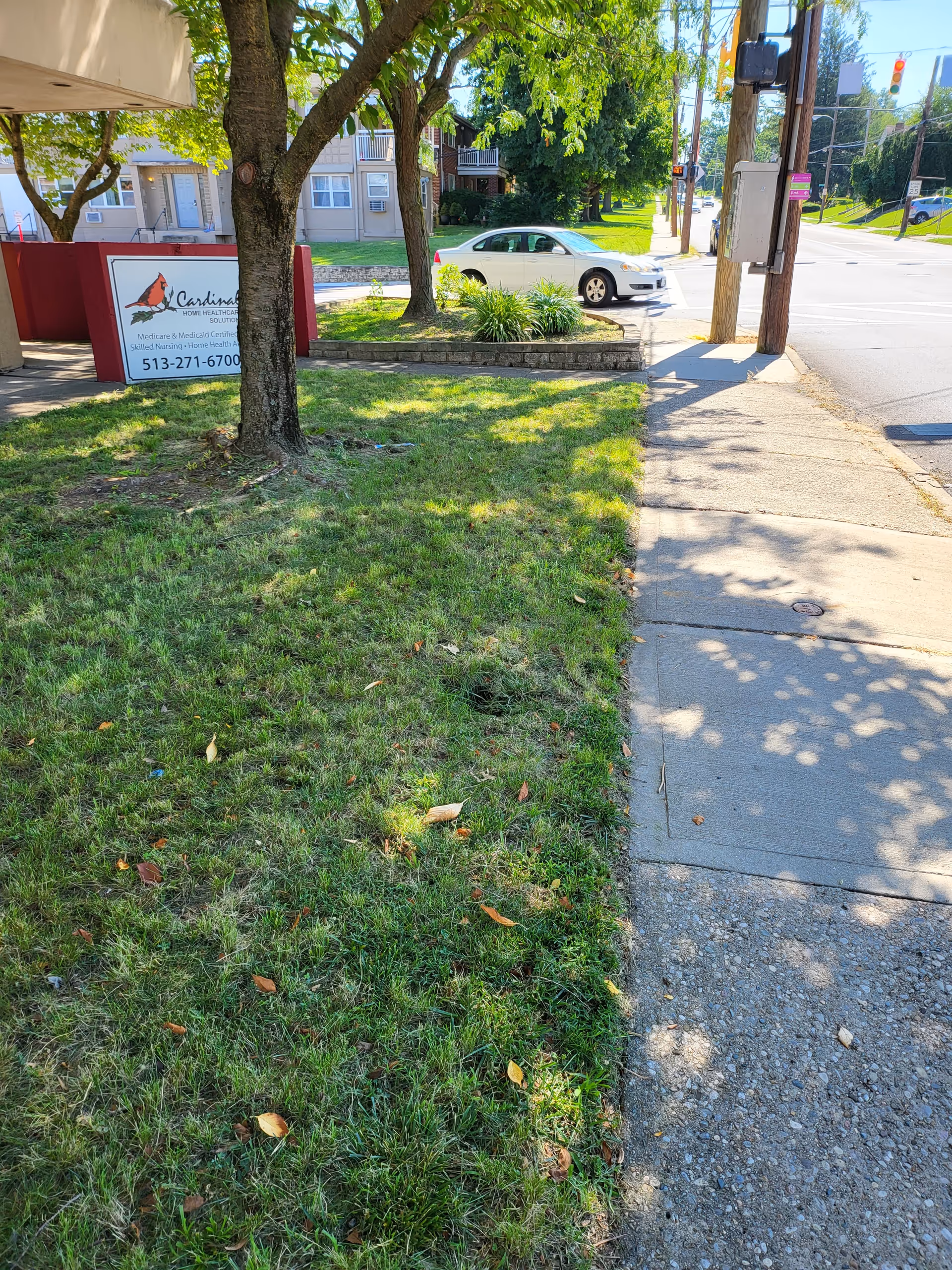 Exterior view of Cardinal Home Healthcare Solutions with sign, trees, and sidewalk.