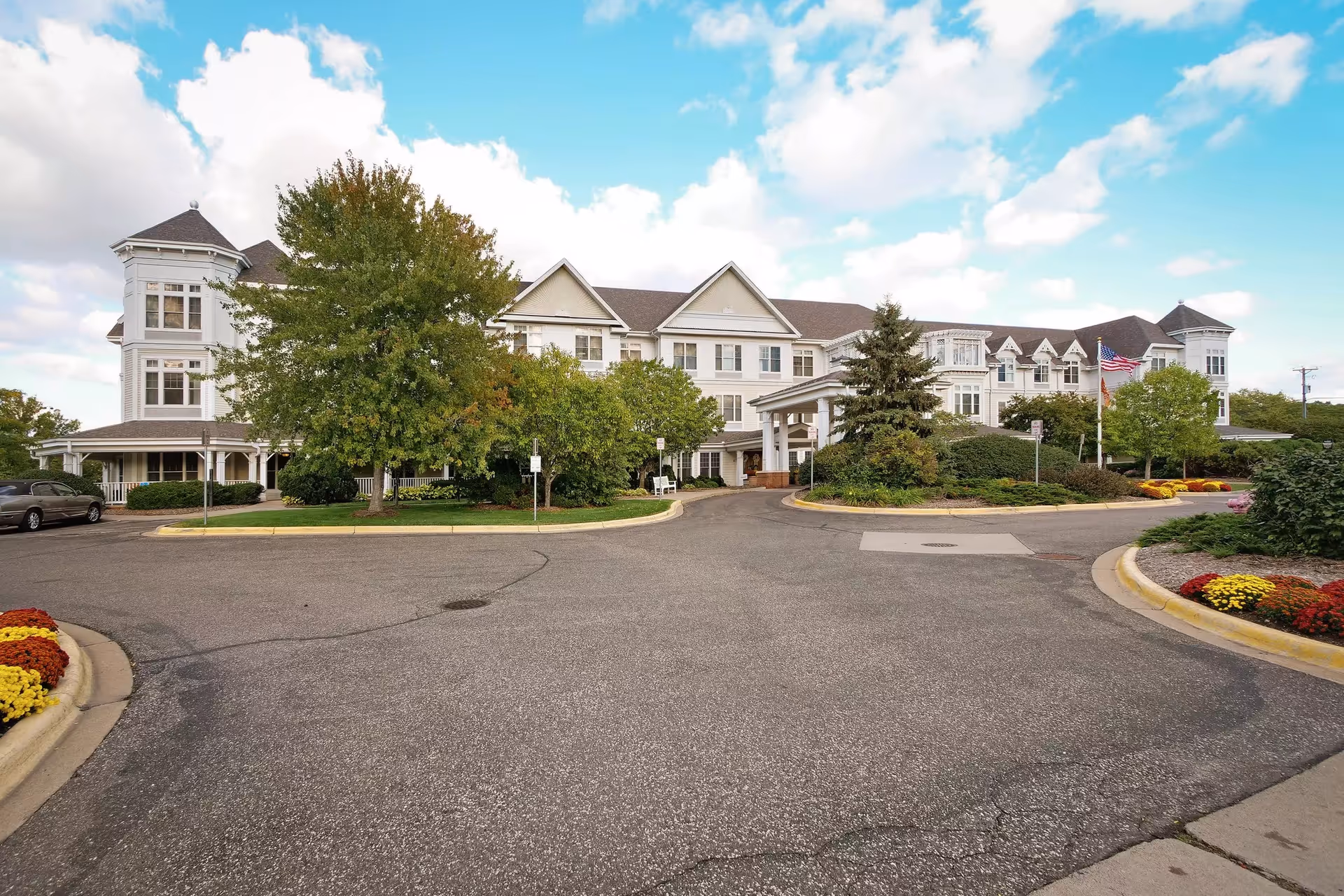 Large senior living facility with a circular driveway and landscaped front entrance.