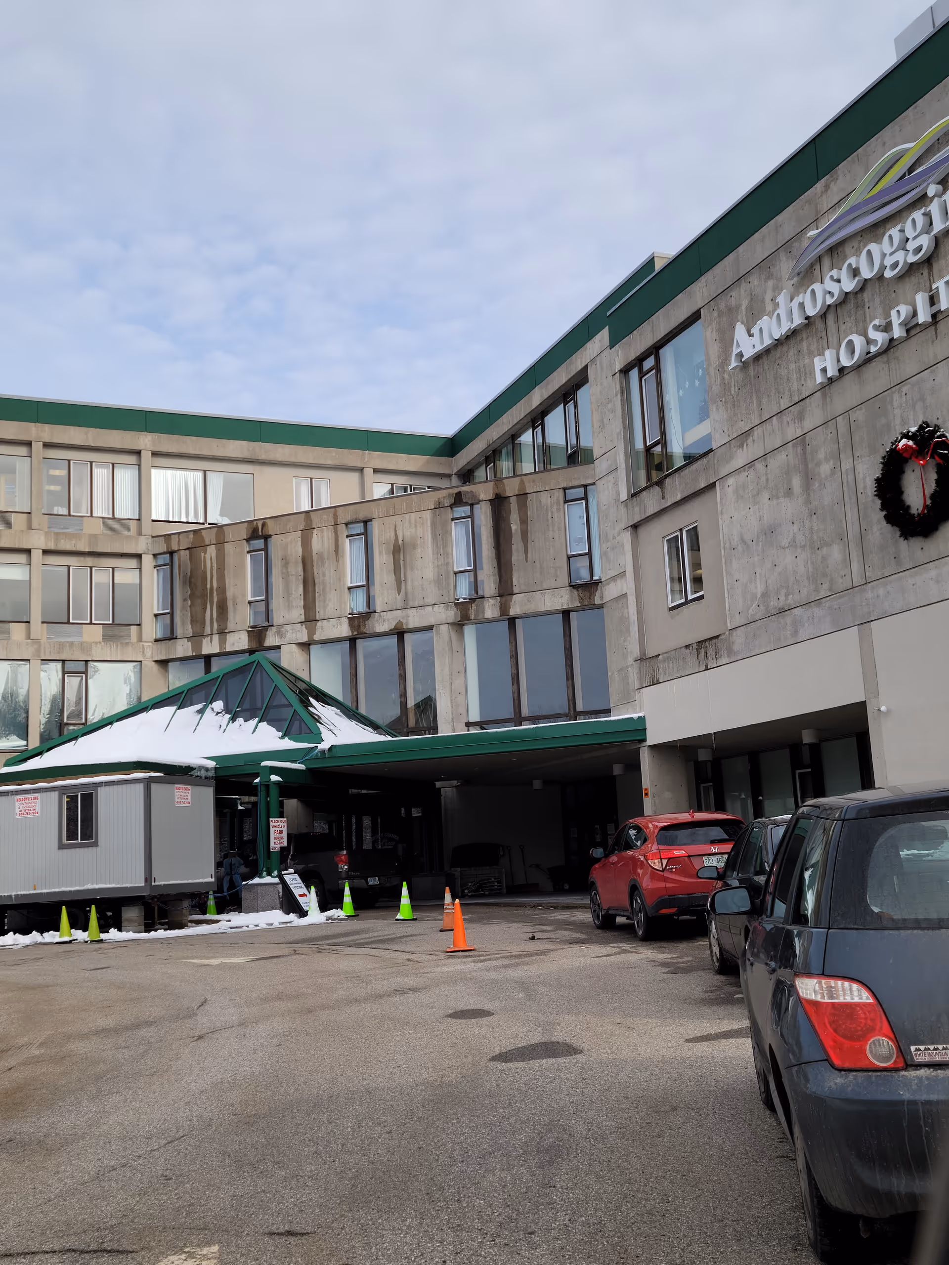 Exterior view of Androscoggin Valley Hospital entrance with parked cars.