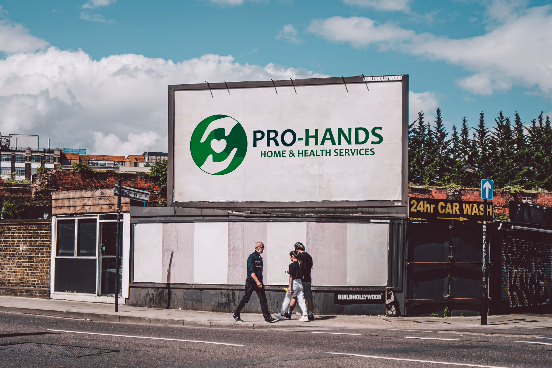 Outdoor street view with three pedestrians beside a large Pro-Hands sign on a building.