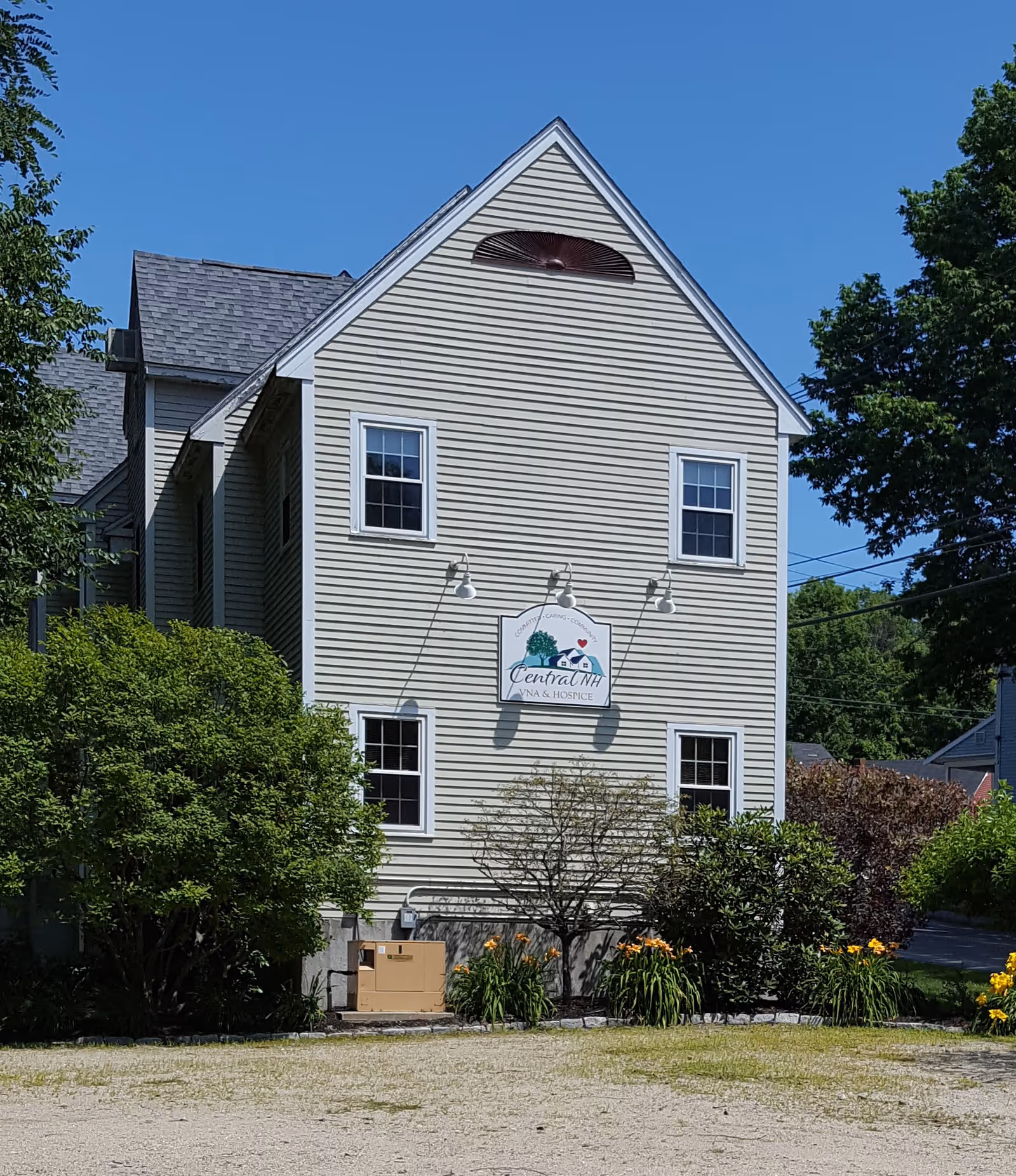 Exterior view of a beige two-story building with a sign and landscaped front yard.