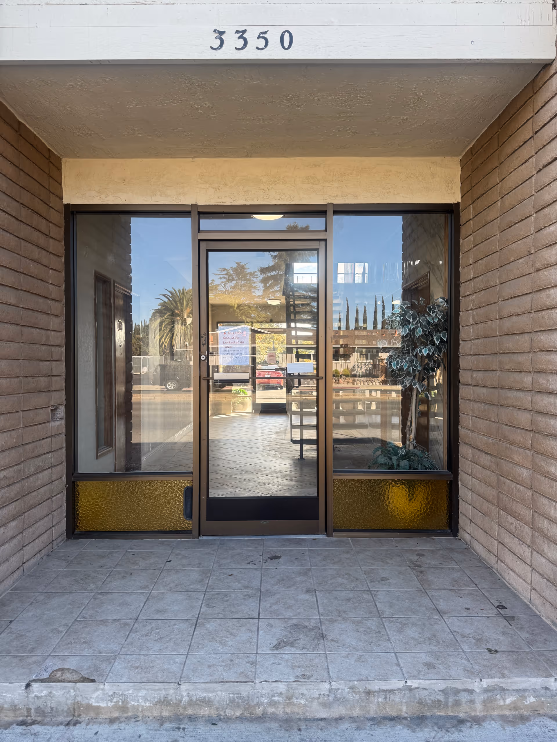 Glass front entrance with a door and side glass panels, brick walls, and a tiled entryway.