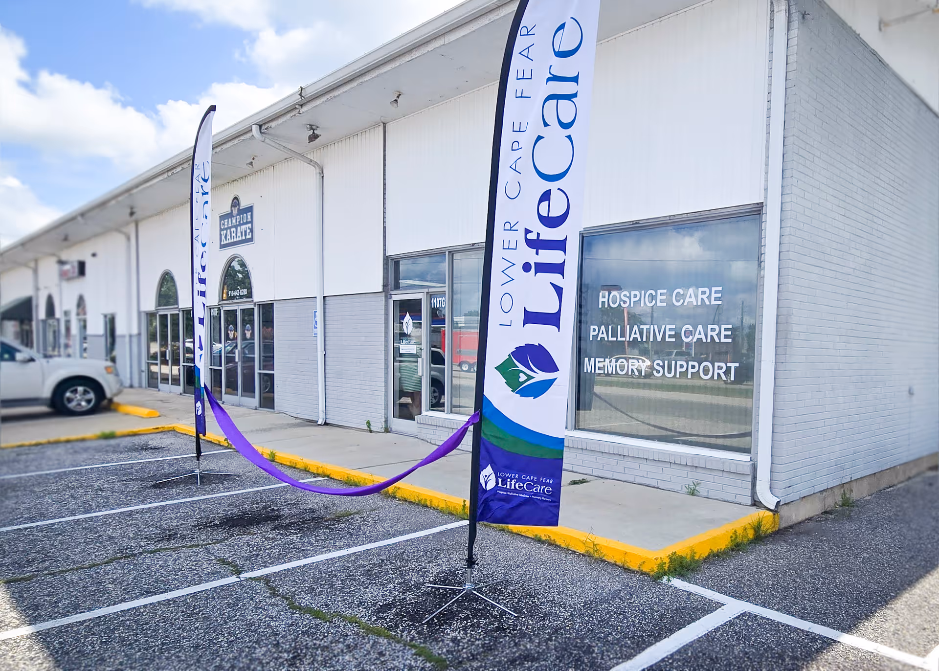 Exterior view of a lifeCare facility with entrance banners and a parking lot