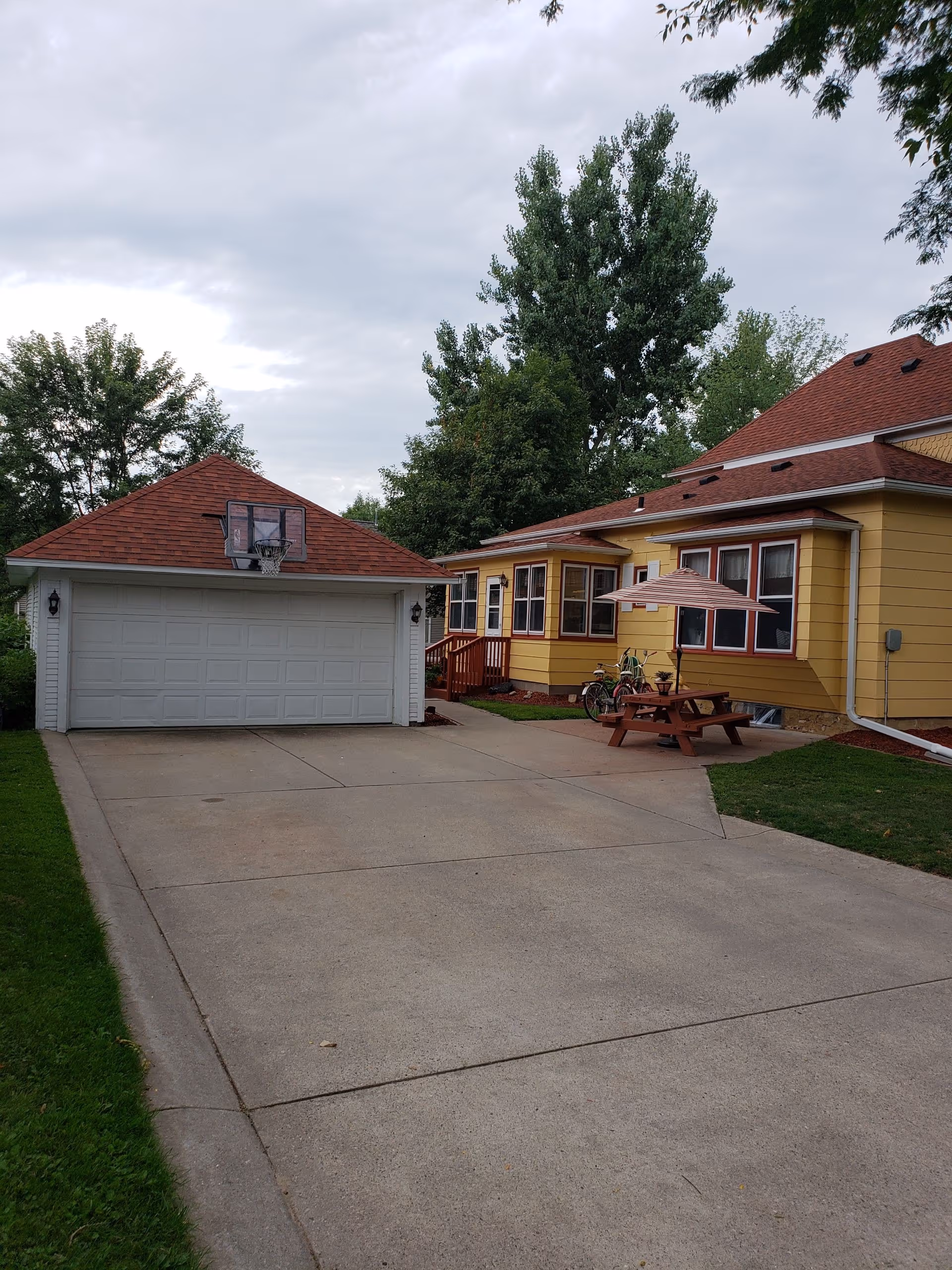 Long driveway leads to a yellow facility with a garage, porch, and outdoor picnic table.