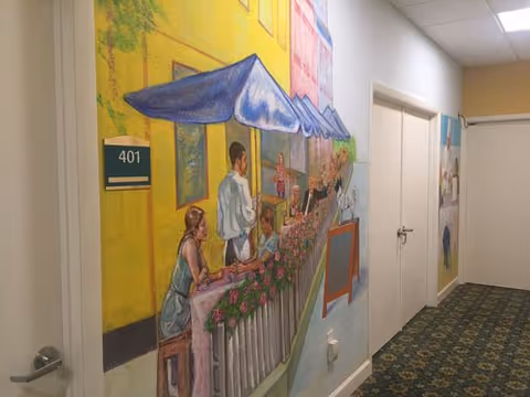 Colorful mural of a street market decorates a hallway inside a senior living facility.
