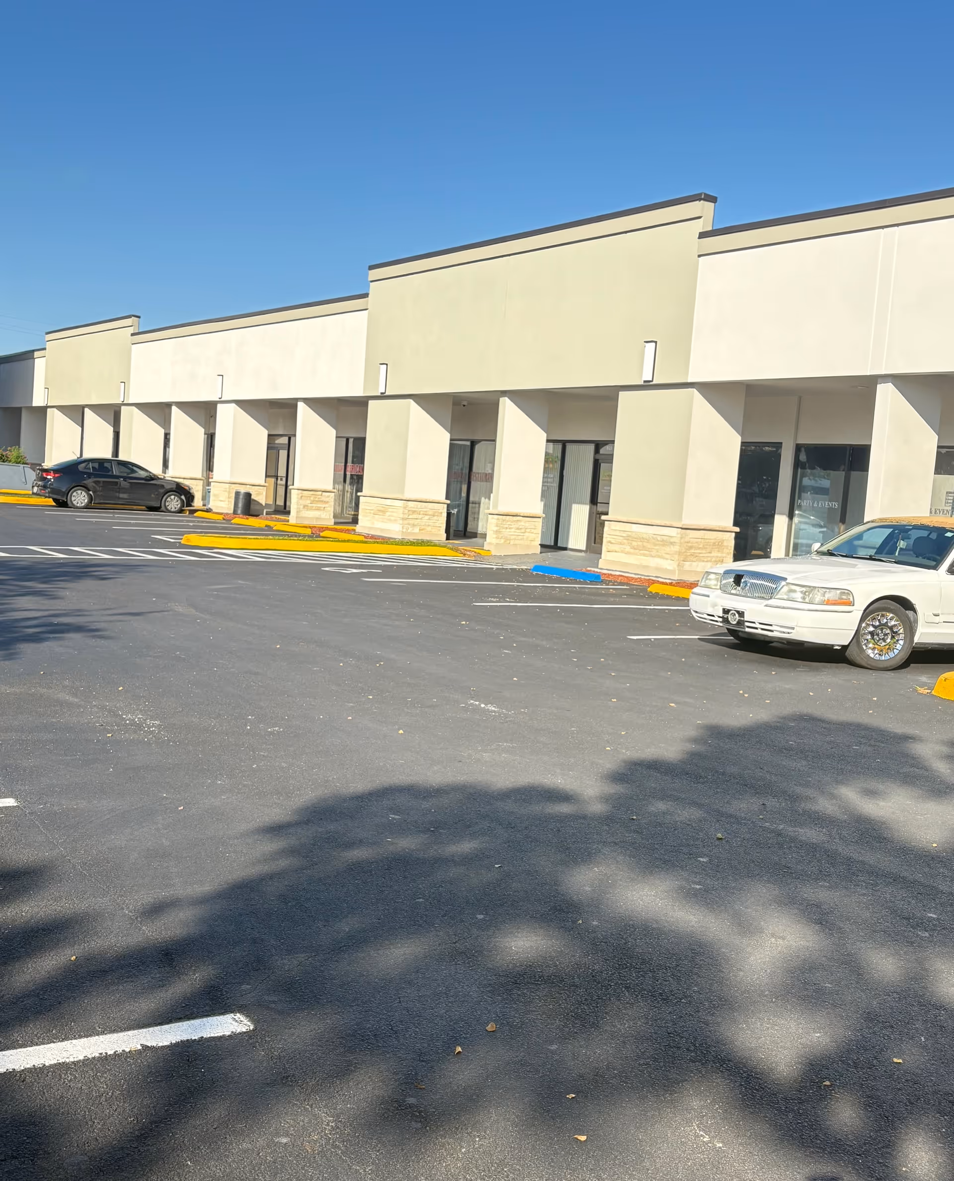 Exterior view of a beige, single-story senior care facility with a parking lot.