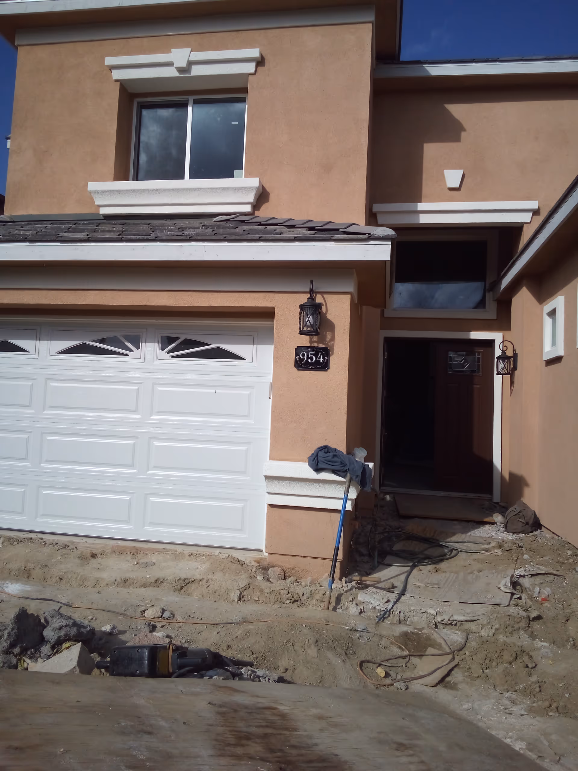 Tan stucco house with white garage door and front entrance under construction.