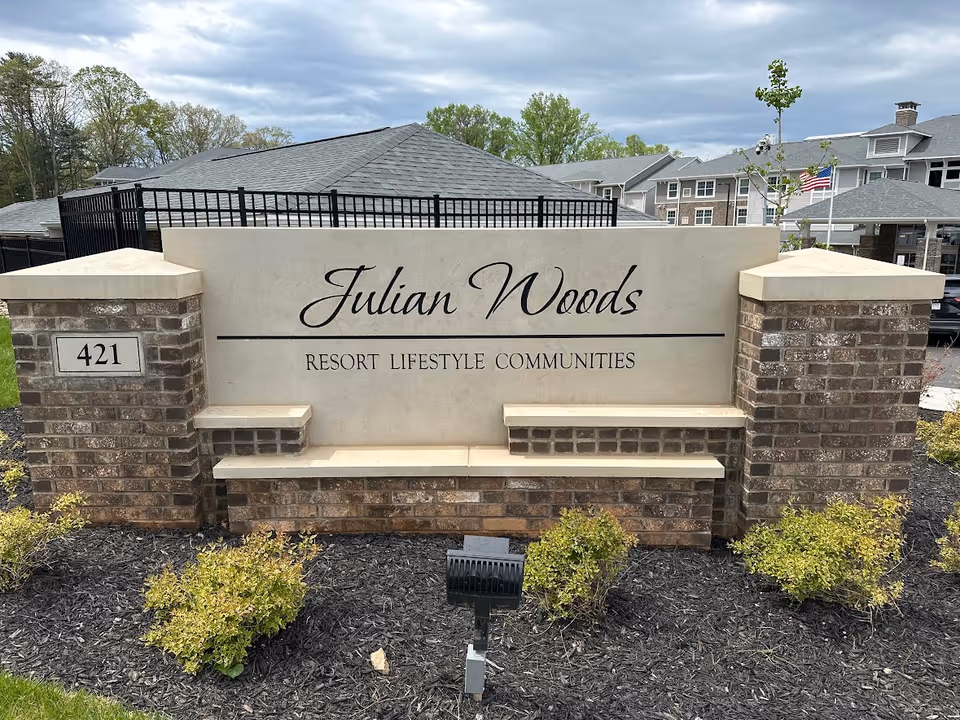 Stone entrance sign that reads "Julian Woods Resort Lifestyle Communities" with the address 421 in front of the community buildings.