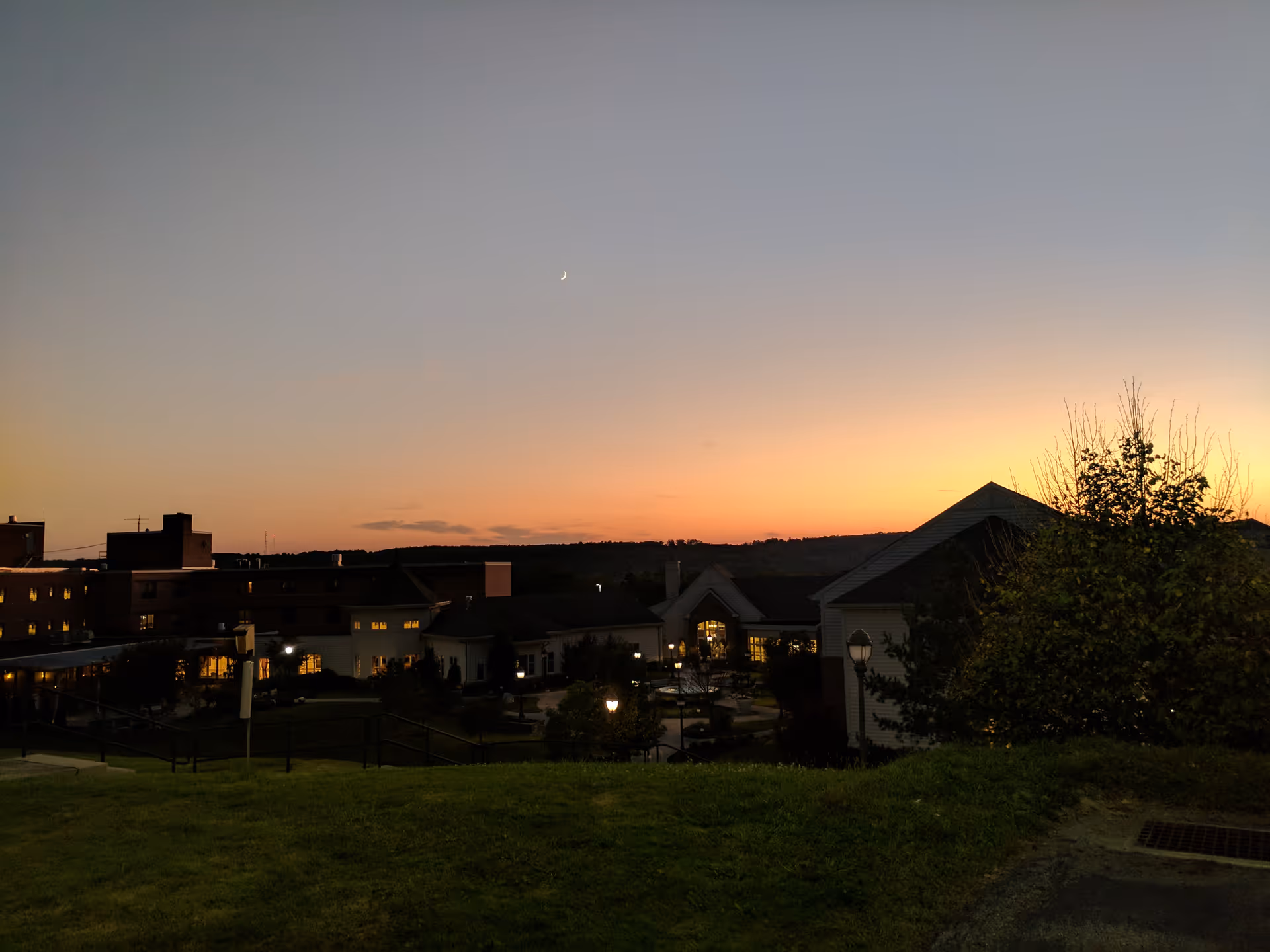 Sunset over a senior living campus, with lit walkways and a front-facing building.