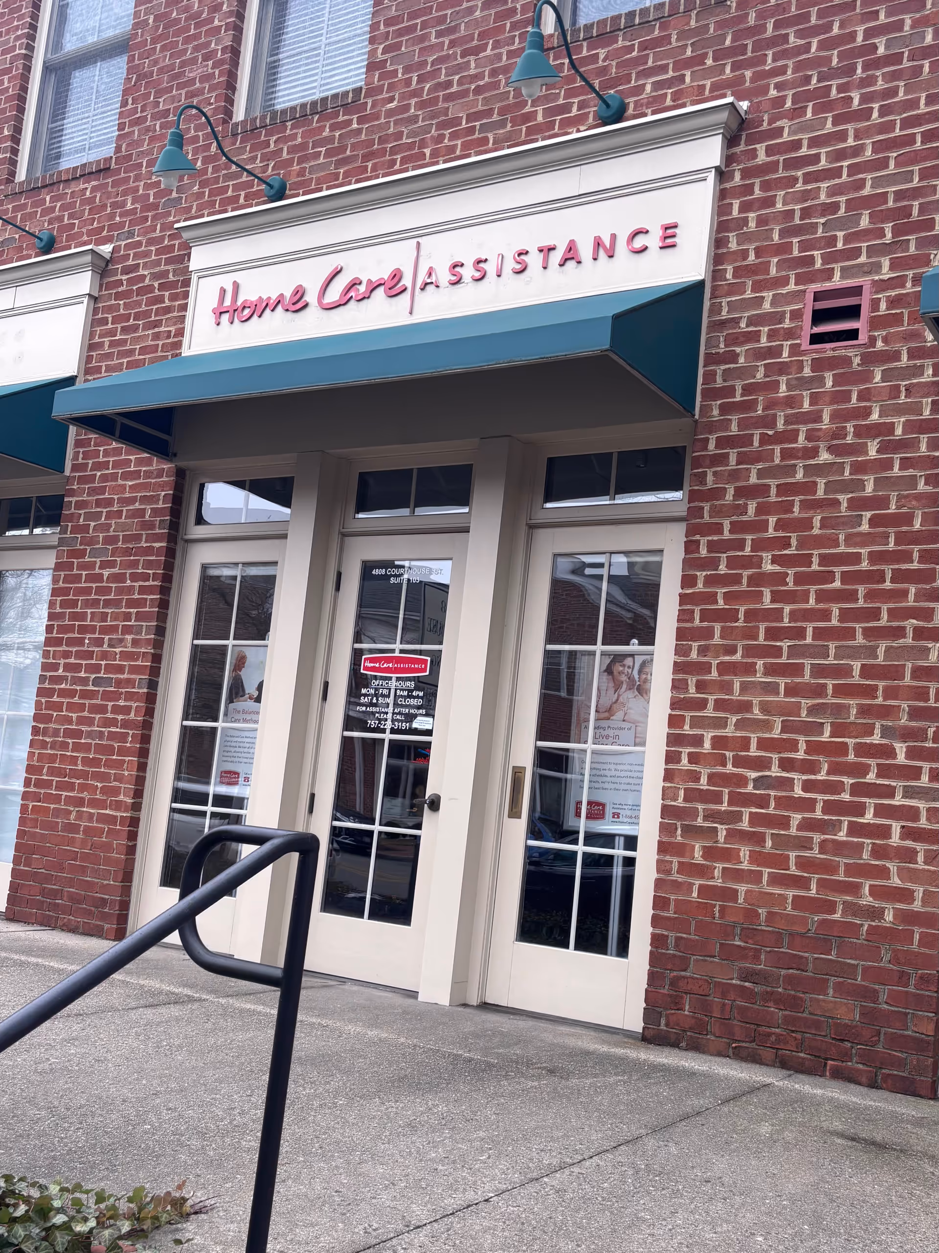 Brick storefront shows Home Care Assistance entrance with glass doors and teal awning.