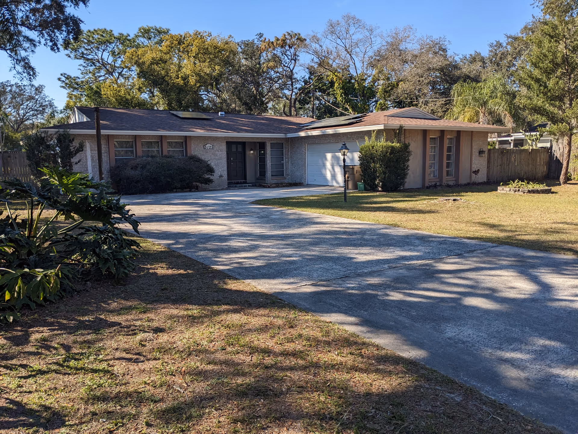 Single-story assisted living facility front with driveway, lawn, and trees.