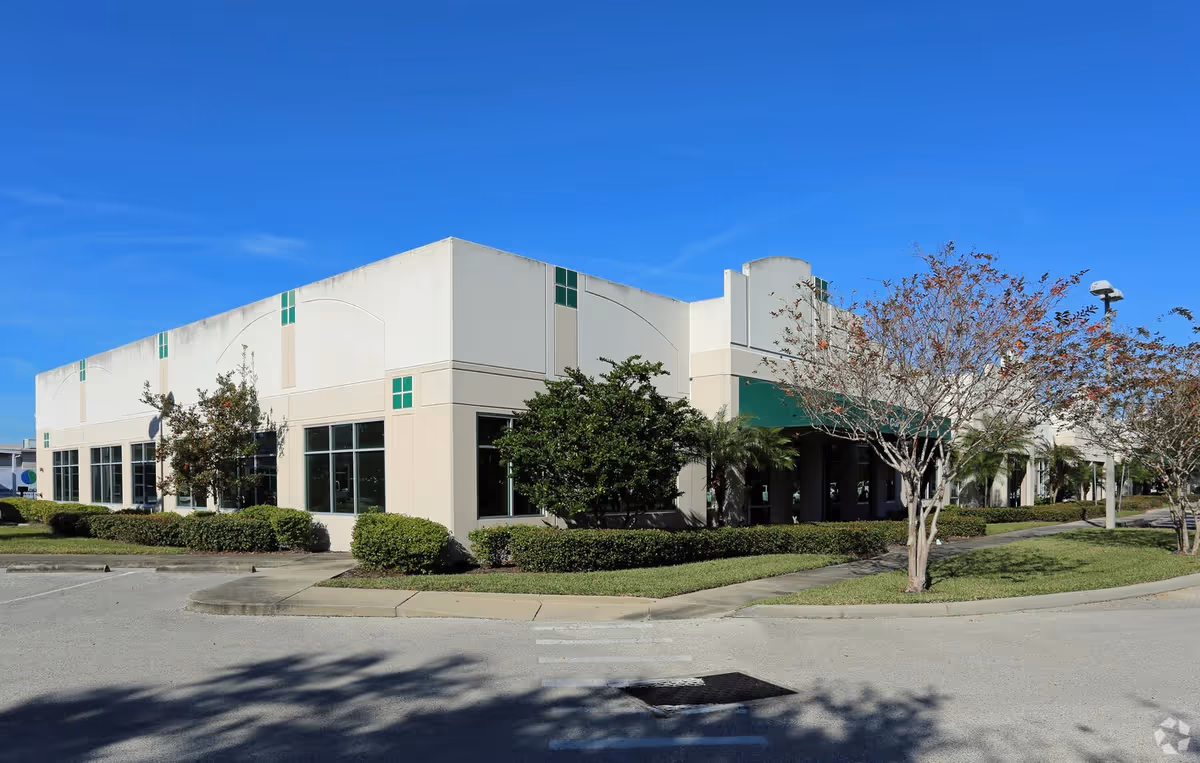 Exterior view of a beige senior care facility with manicured shrubs and blue sky