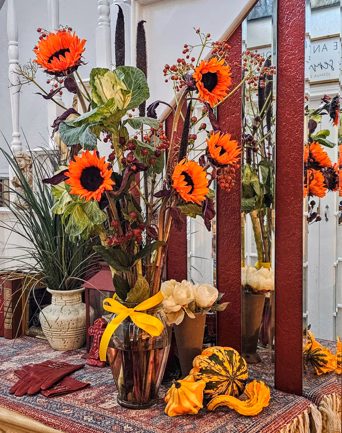 Autumn centerpiece with orange sunflowers, pumpkins, and ribbons on a decorated table.