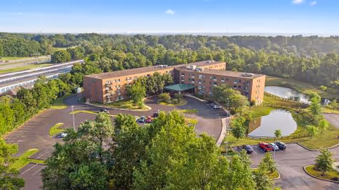Aerial view of The Village at Eastgate Retirement Community showing brick buildings, parking, and surrounding trees.