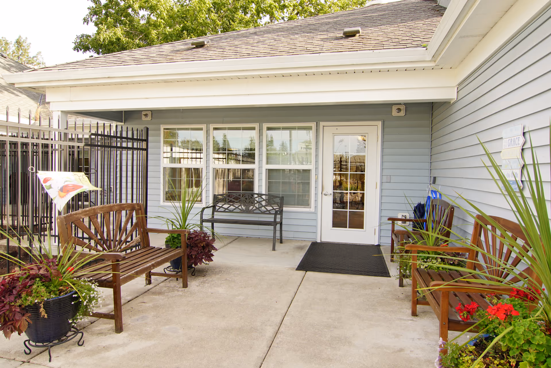Covered entrance patio with benches, potted plants, and a glass door leading into the facility.