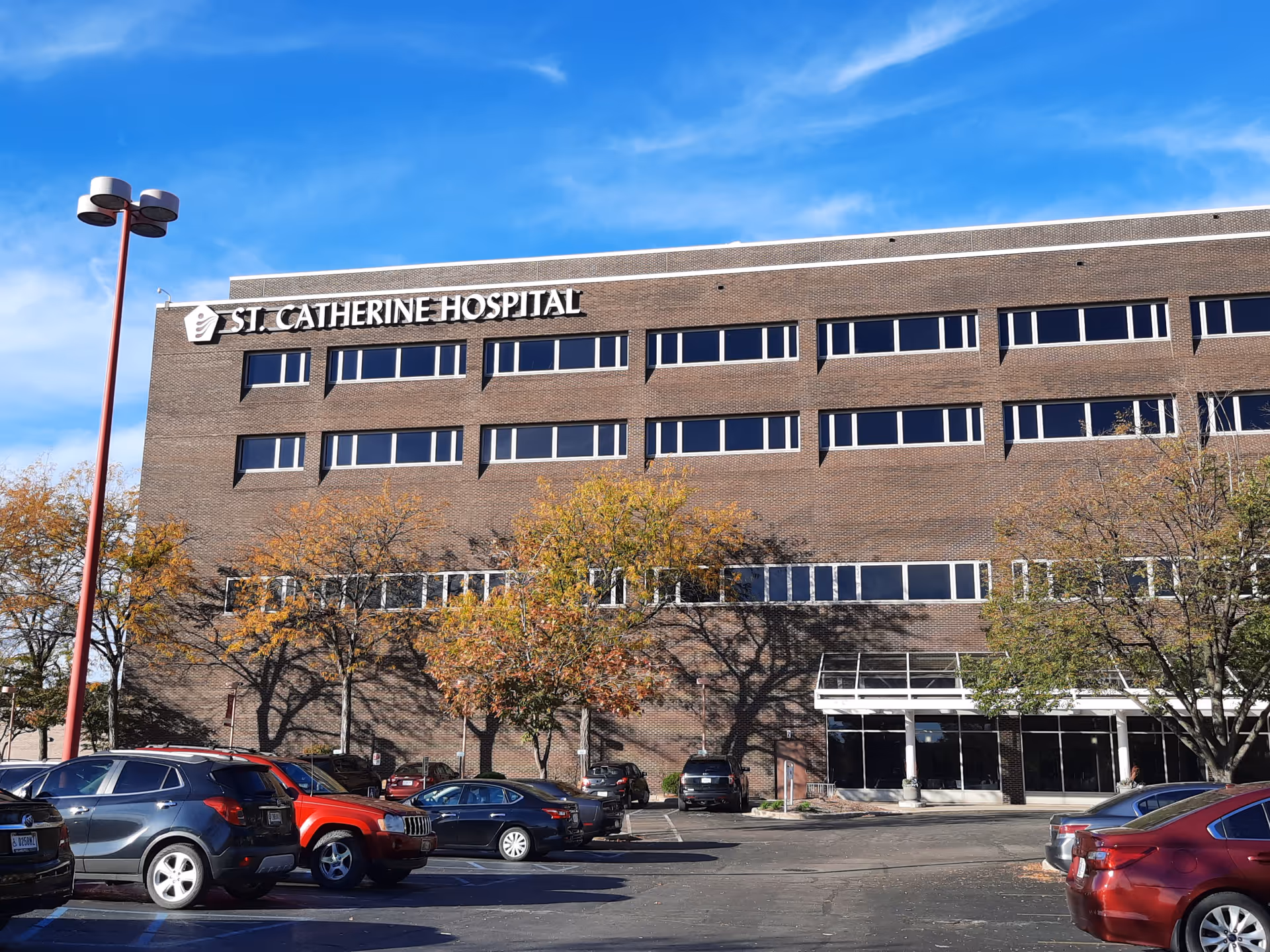 Brick hospital building with St. Catherine Hospital sign, rows of windows, and a parking lot.