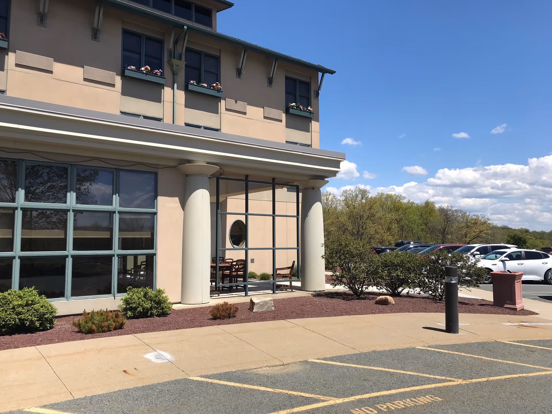 Exterior view of Personal Care at Allied Terrace, with glass entrance, columns, and parked cars.