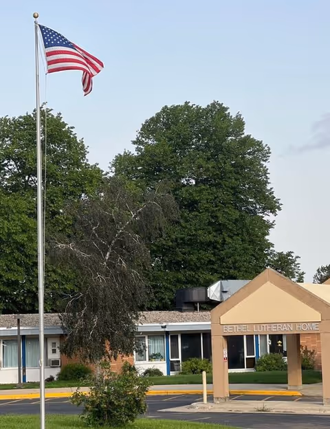 American flag flies beside Bethel Lutheran Home entrance on a sunny day.