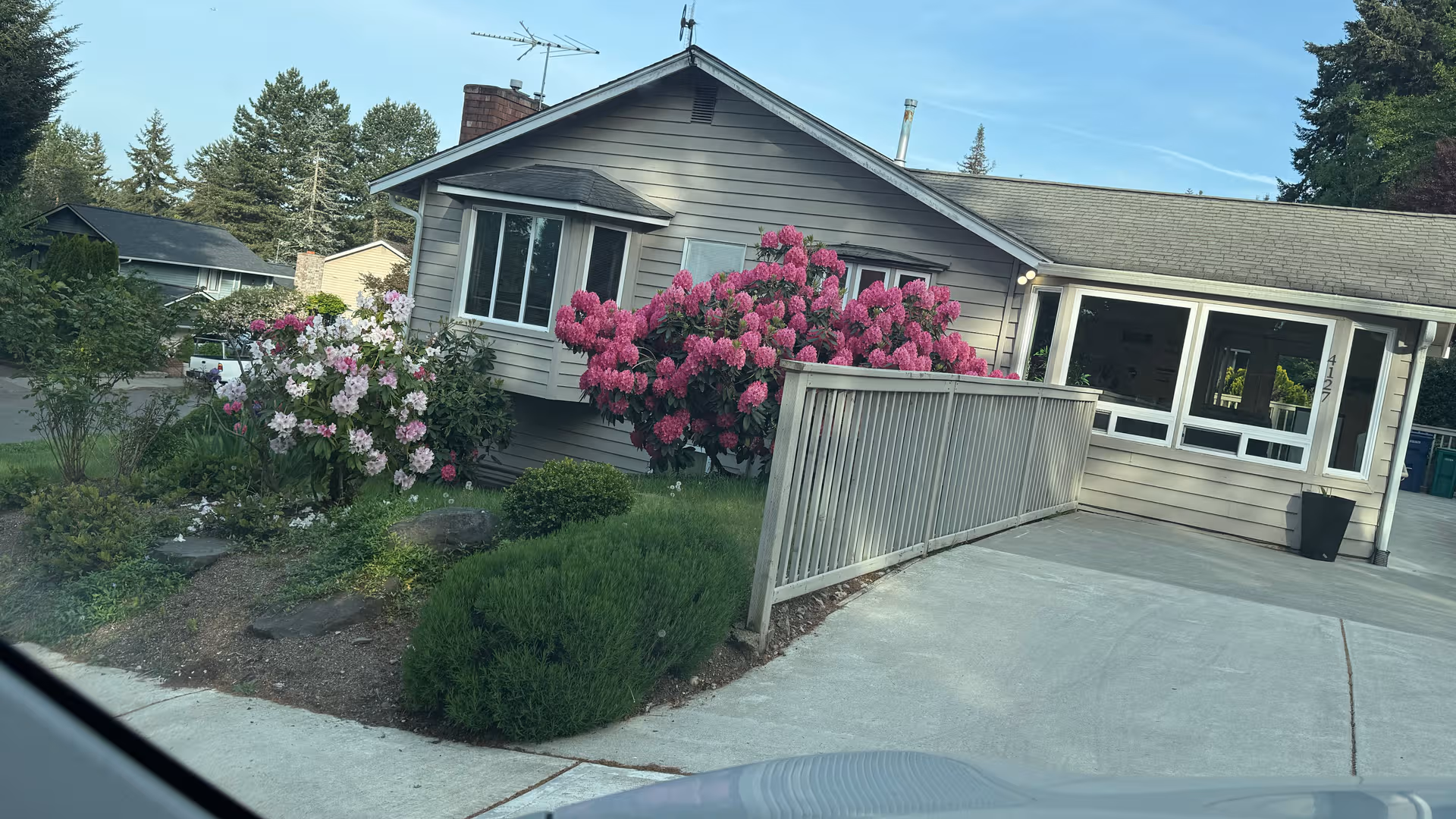 Front exterior of a single-story senior care building with blooming shrubs and a concrete walkway.