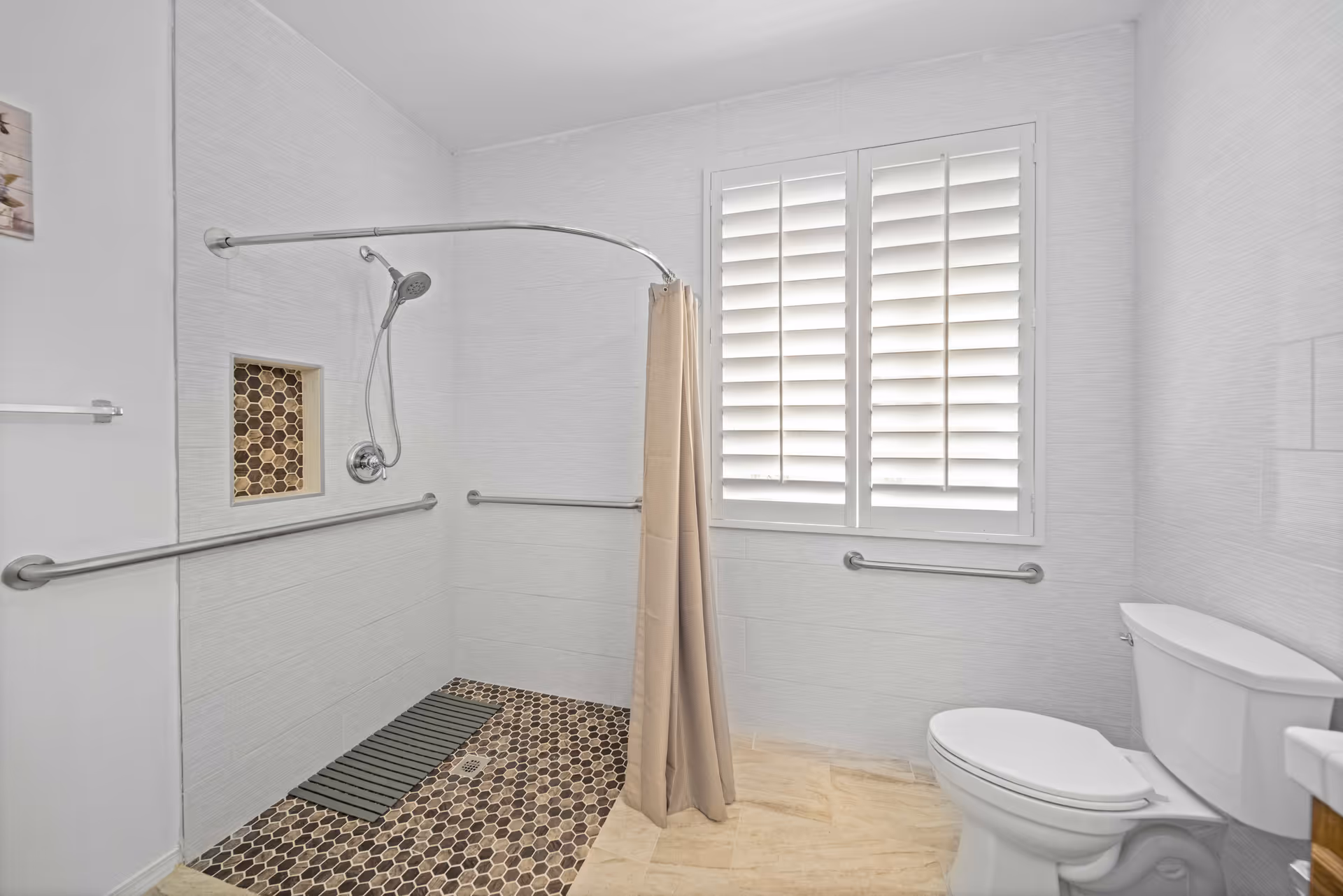 Accessible bathroom featuring a walk-in shower, grab bars, a toilet, and a shuttered window.