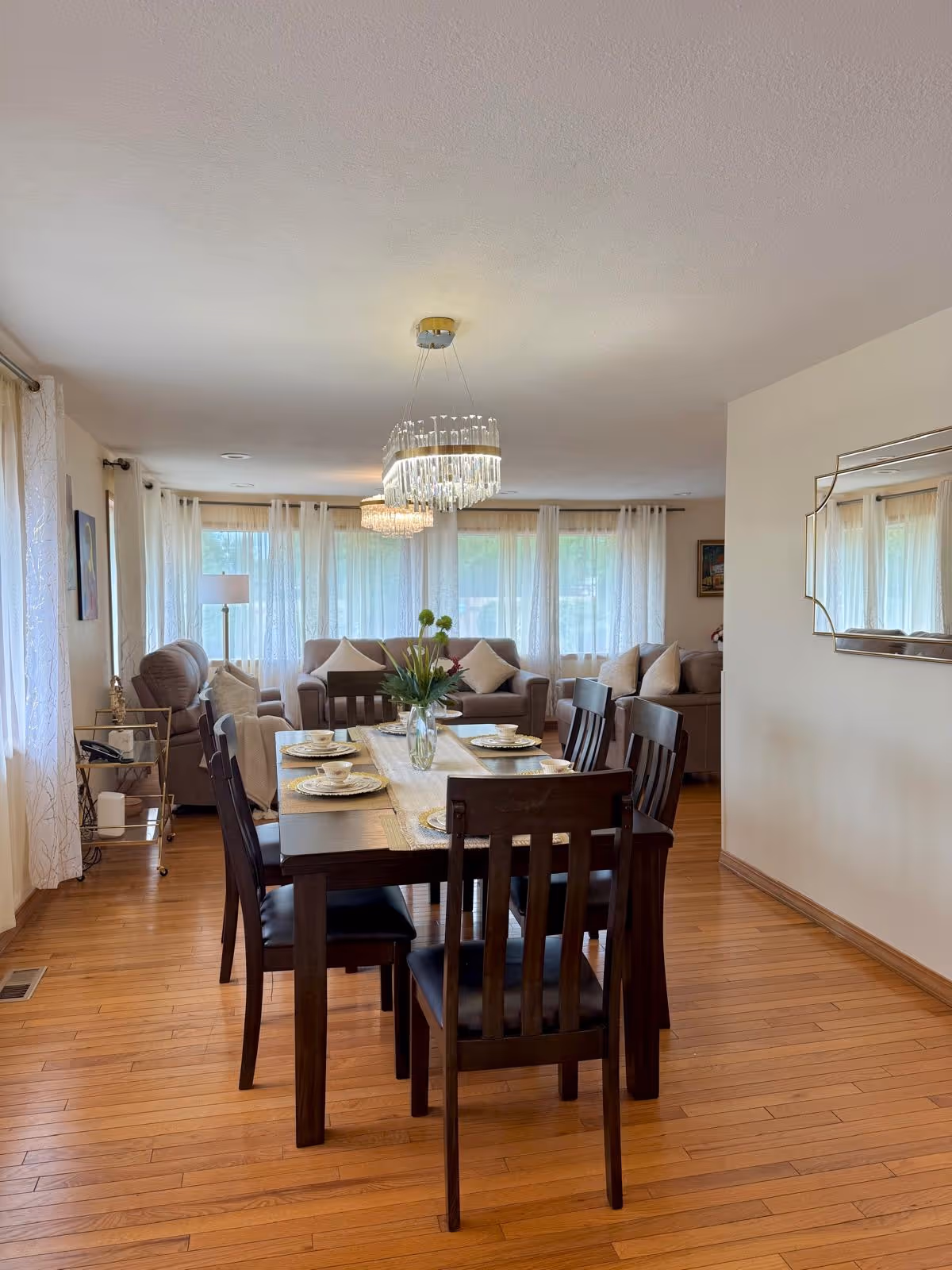 A wooden dining table set for a meal in a bright open dining area with couches.